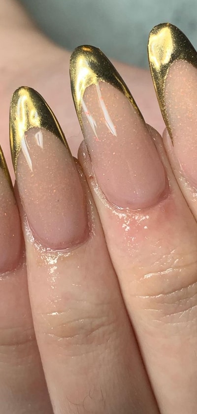 The post features 23 different looks that could be achieved with a nude polish and gold glitter. It can be hard to choose which look you want to do, so the post helps by showing all of the possibilities. Nude nails are timeless, but adding glitter can make them feel more glamorous for any occasion. Gold is also thought to have healing powers so it could be beneficial for your nails as well! #nudegoldnails #nudegoldnailart #nudegoldnaildesigns #nudegoldacrylicnails