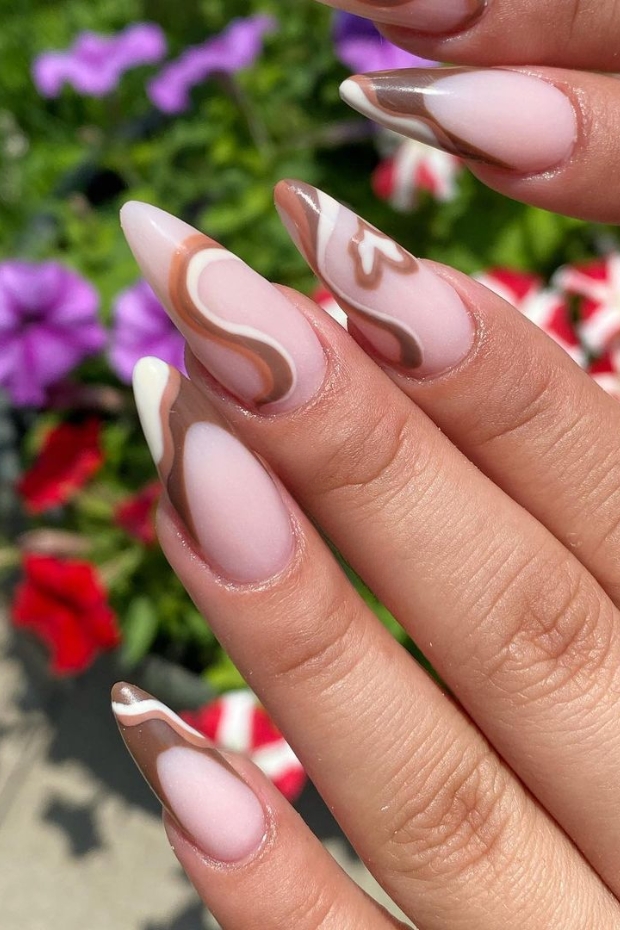 Close-up of elegantly manicured stiletto almond nails showcasing their sharp, tapered shape and glossy burgundy polish