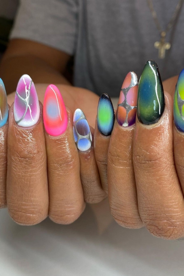 Close-up of trendy almond-shaped nails with a bold and edgy design in vibrant colors and metallic accents