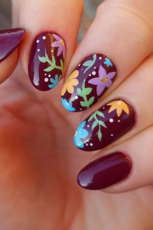 Colorful floral motif on maroon-colored nail