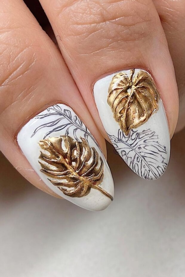 White nails with gold leaf accents arranged in a leaf pattern