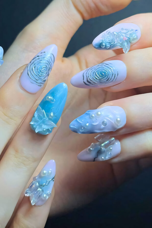 Blue and white intricate nail art with pearls, flowers, and butterflies