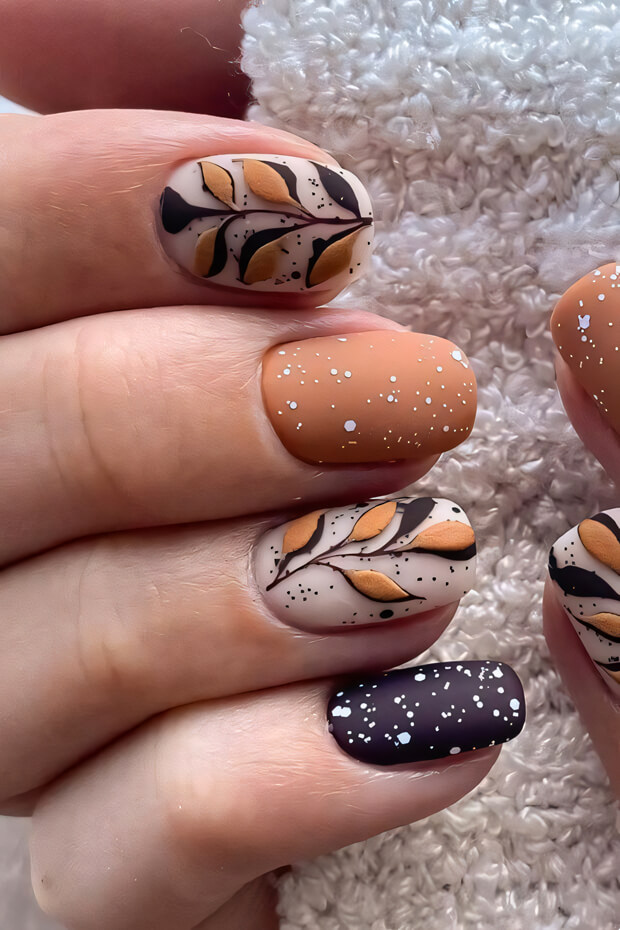 Brown, black, and white manicure with intricate leaf patterns