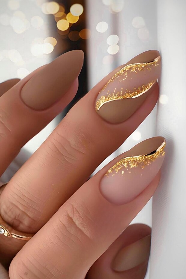 Gold glitter accent on brown almond-shaped nail