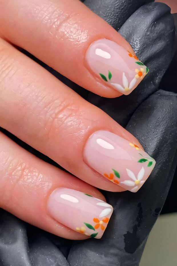 Pink manicured nail with white flowers and green leaves