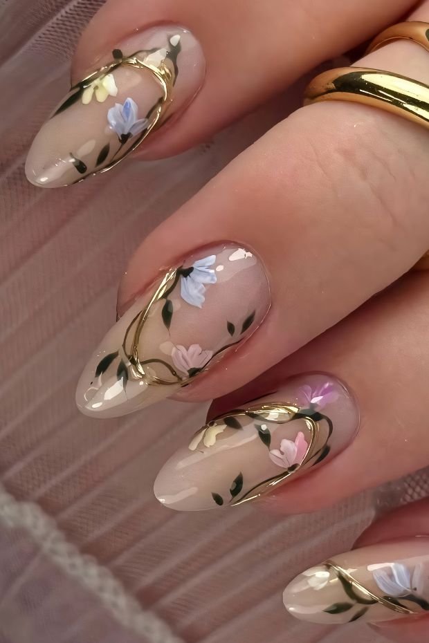 Floral nail art design with gold accents on elegant nails featuring pink and blue flowers with green leaves.