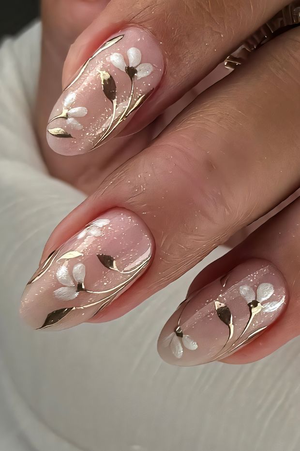 Elegant floral nail art with gold accents on nude background designed for a chic and sophisticated look.
