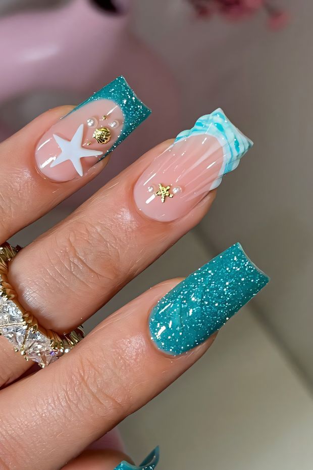 Aquatic nail design with teal glitter, starfish accents, and beach-inspired elements for a trendy summer look.