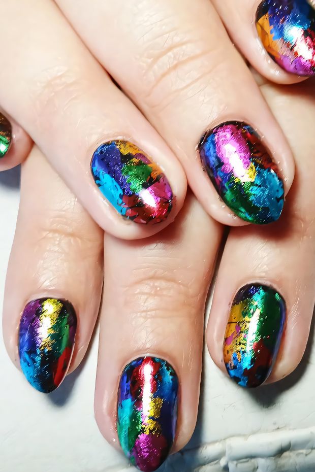 Colorful nail design with rainbow splatter effect, showcasing vibrant hues and glossy finish for striking style.