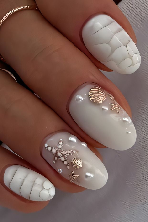 Coastal-inspired nail art with white base, textured designs, 3D sea elements, shells, pearls, and starfish detailing.