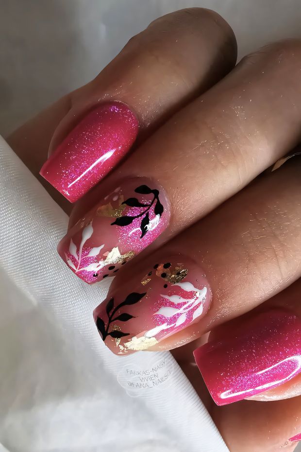 Vibrant pink nails with floral designs and gold accents, showcasing a unique nail art style.