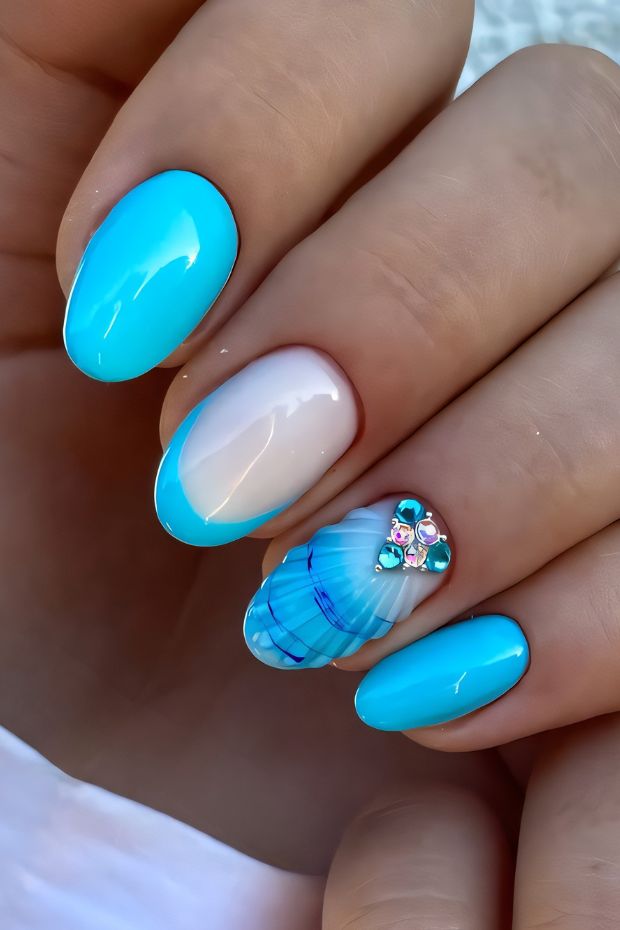 Ocean-inspired bright blue nail art with seashell design and colorful gems for a trendy summer look.