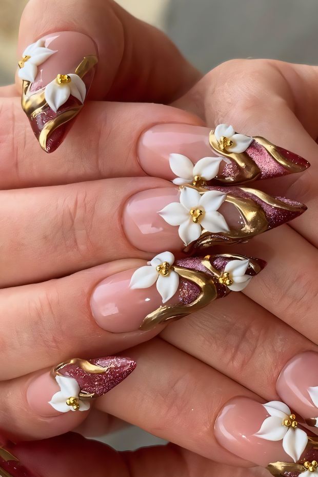 Beautiful floral nail art with gold accents and elegant burgundy and nude colors for a stunning design.
