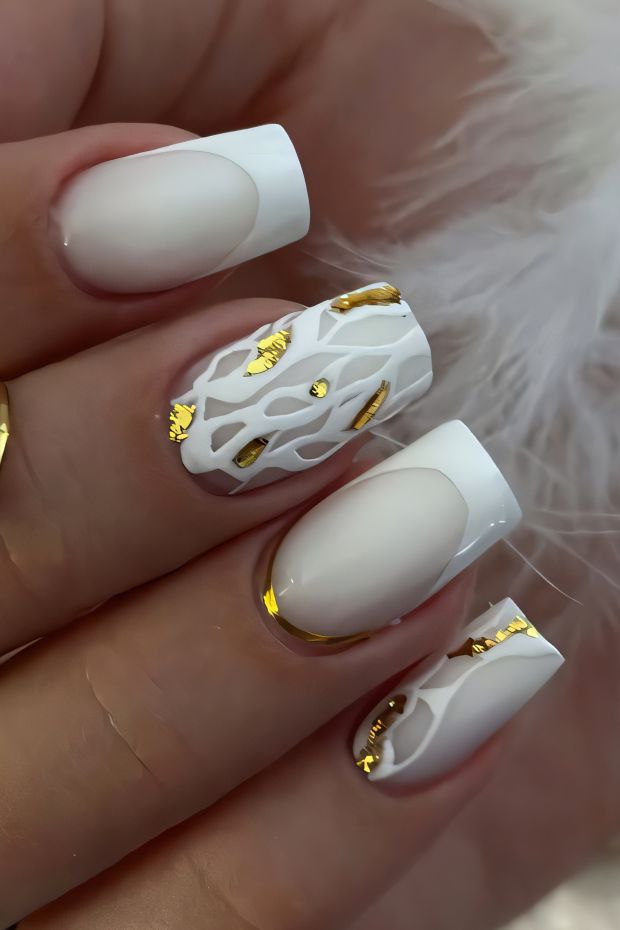 Chic white and gold nail design featuring intricate patterns and glossy accents for a stylish look.