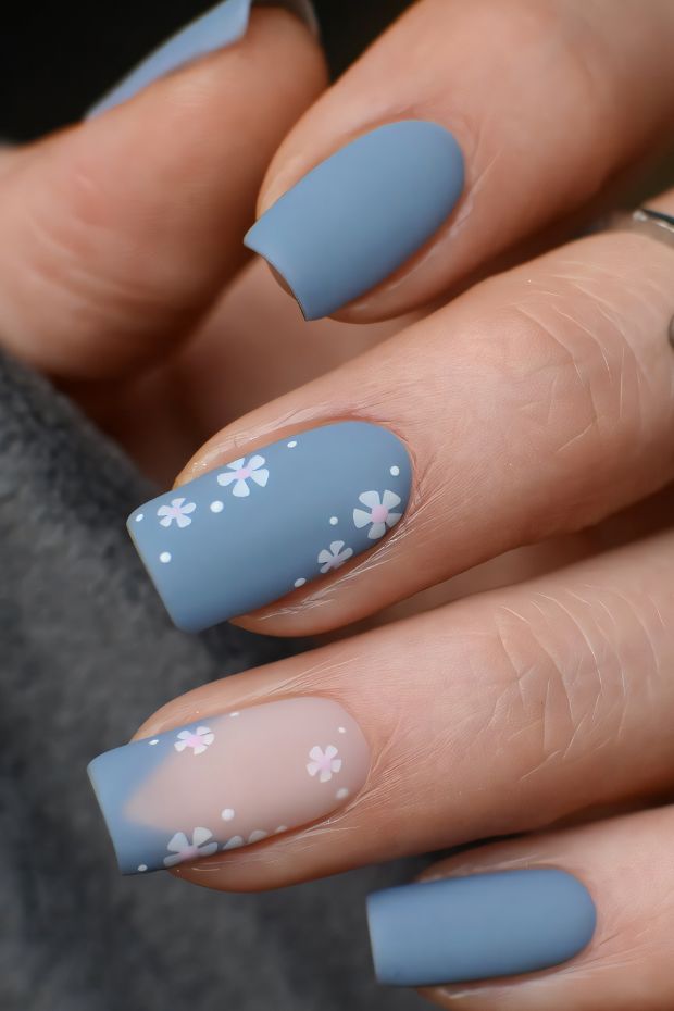 Chic blue nail design with floral accents and matte finish, perfect for trendy nail art enthusiasts.