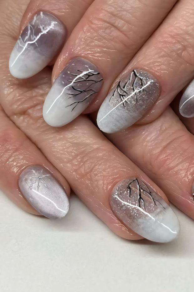 Winter-inspired ombre nail art featuring frosty branches and sparkles for a festive look.