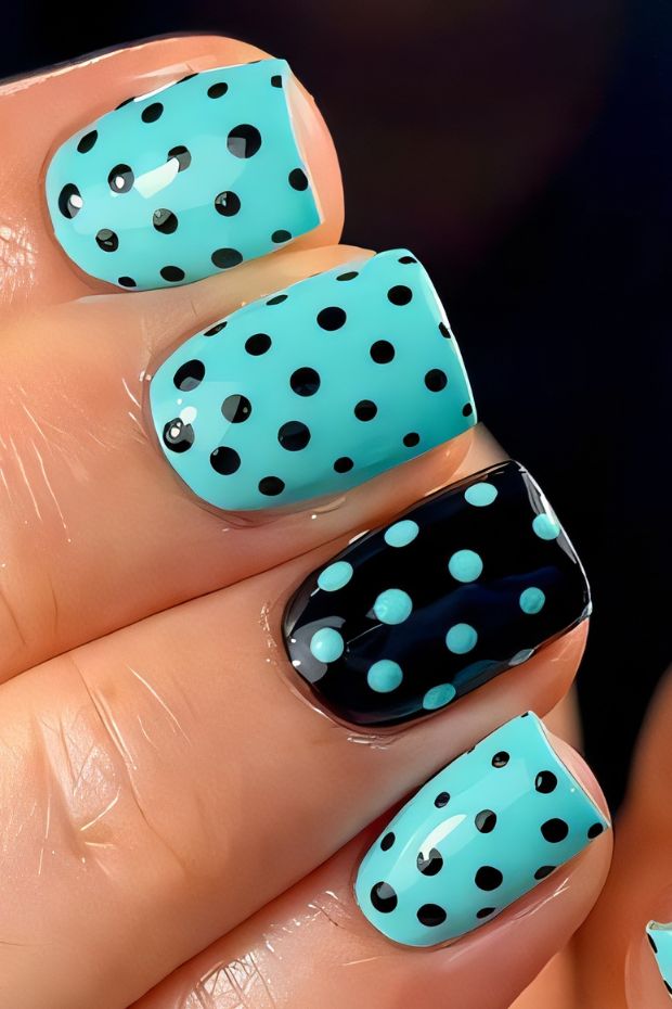 Aqua and black polka dot nail design featuring varying sizes of dots on each nail for a playful effect.