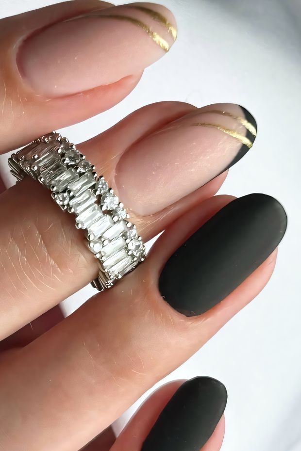 Chic black matte nails accented with elegant gold lines and nude nails featuring black tips, unique nail art design.