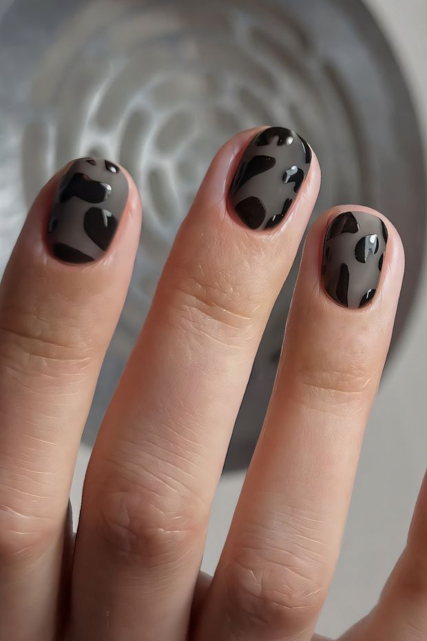 Black nail design featuring abstract patterns with a glossy finish for a modern look.