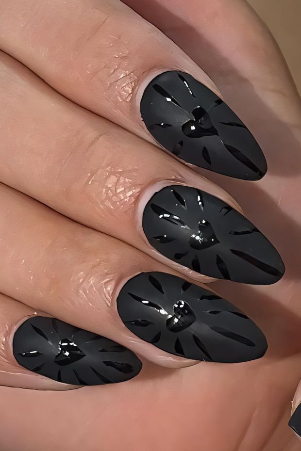 Black nail design with unique cutouts and glossy accents for a bold look.