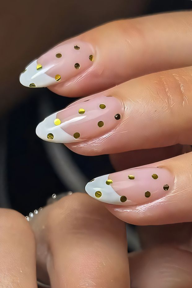 Elegant polka dot nail design with gold dots on nude and white tips, showcasing playful nail art creativity.