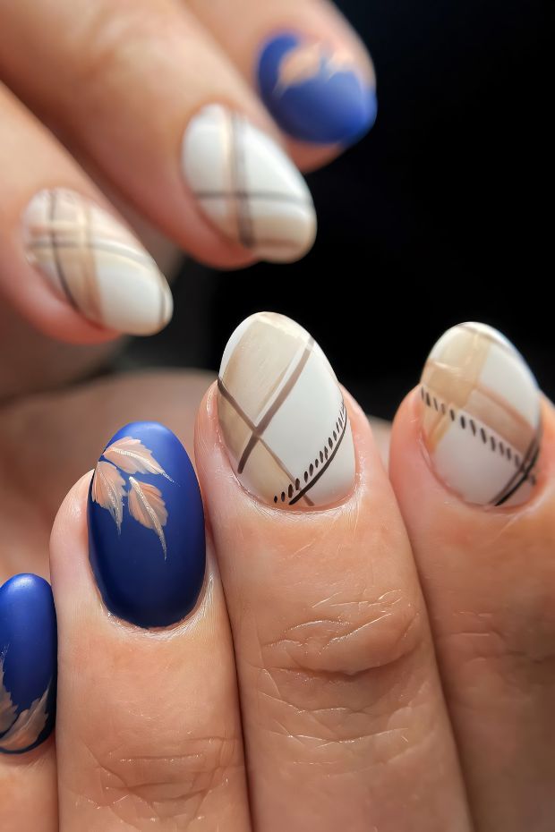 Winter nail art featuring plaid patterns and leaf designs in blue and cream colors.