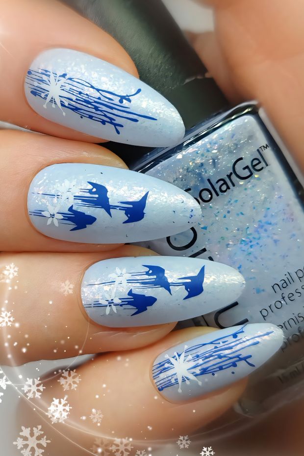 Winter nail design featuring blue snowflakes on a shimmering light blue background with artistic accents.