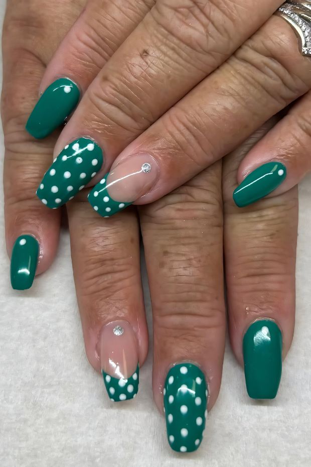 Teal nail design with white polka dots and accent nails featuring a subtle shimmer detail.