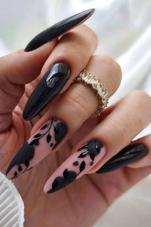 Chic black nail art featuring leaf designs on a mix of glossy black and nude nails.