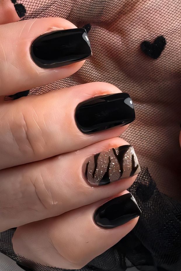 Black nail design with gold glitter accents and artistic patterns for a fashionable look.