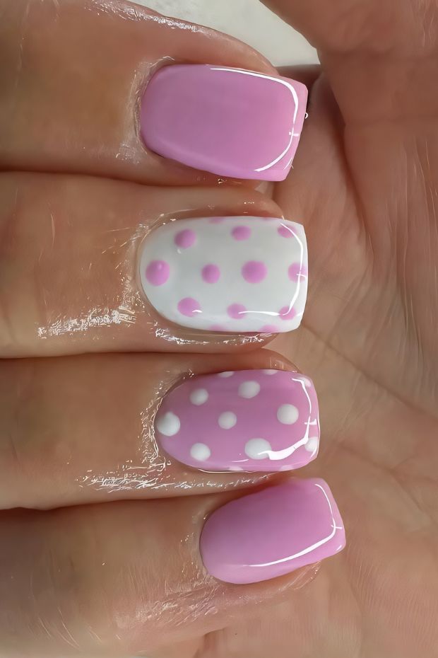 Pink nail art featuring white polka dots on a variety of nail shapes and lengths for a playful look.