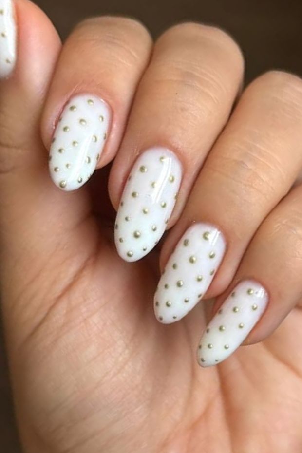 Chic white nail design with gold polka dots for trendy nail art enthusiasts.