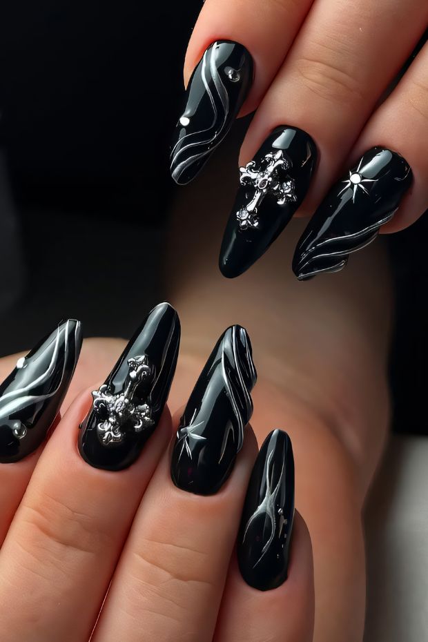 Black nail art featuring white swirls and metallic accents for a chic, stylish look.