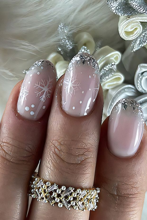 Winter nail design featuring snowflakes, nude base and frosted tips for a seasonal chic look.
