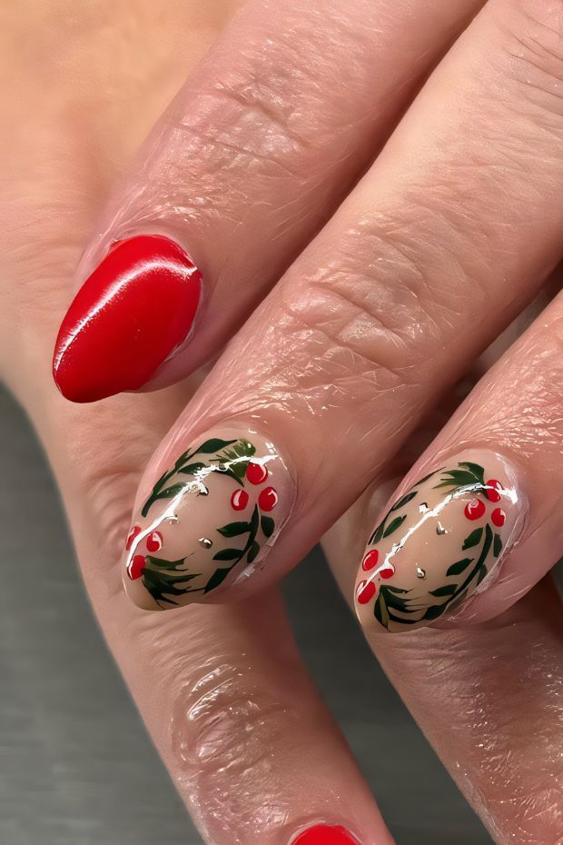 Winter nail art featuring red polish, nude base with holly and berry designs, perfect for festive celebrations.