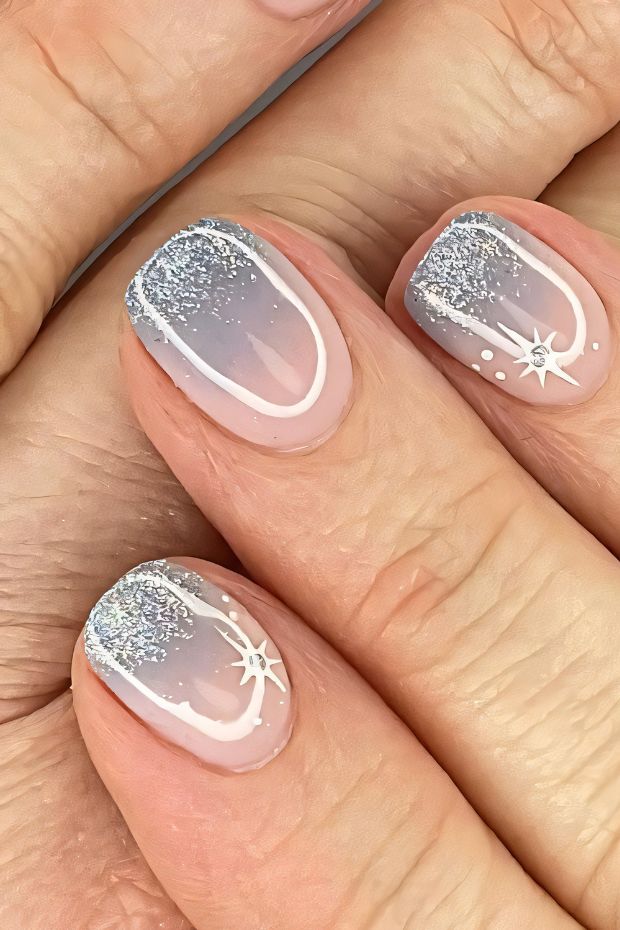 Winter nail design featuring silver glitter, white stars, and a cool gradient for a seasonal look