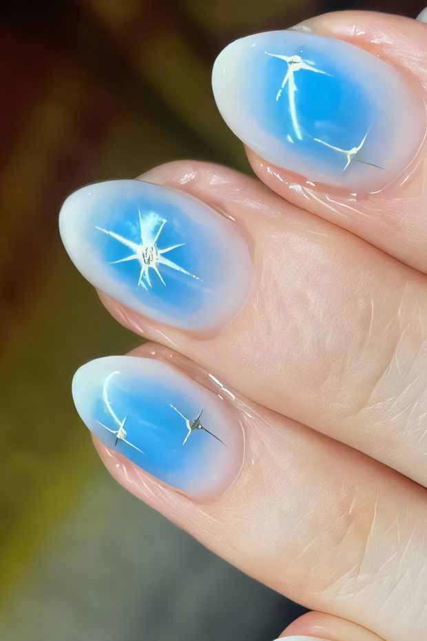 Winter nail design with icy blue gradient and shimmering star embellishments for a festive look.