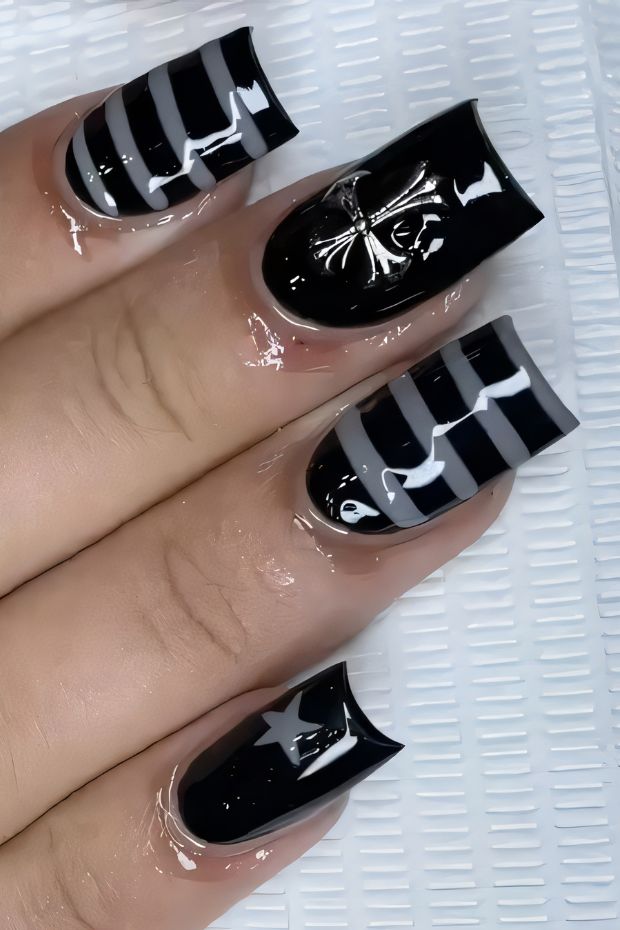 Black nail design with stripes, stars, and glossy finish for stylish nail art lovers.