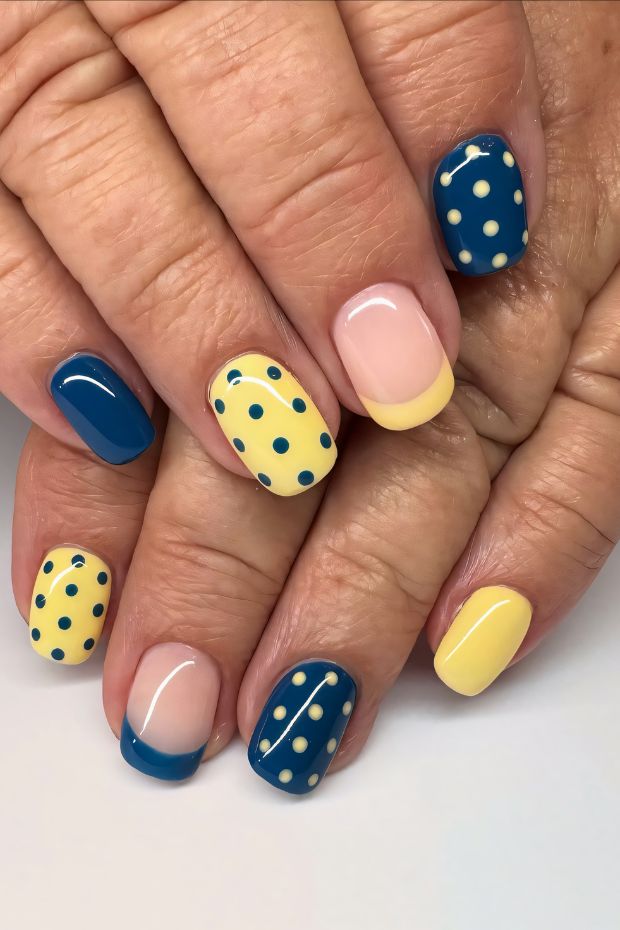 Colorful polka dot nail design featuring blue and yellow shades with a chic French tip accent.