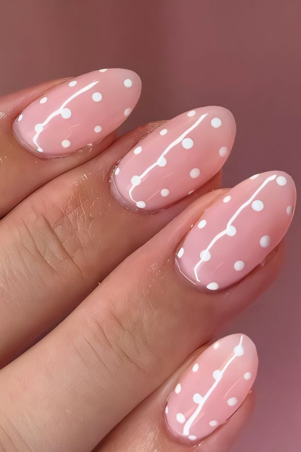 Chic pink nail design with white polka dots for a trendy and stylish manicure.