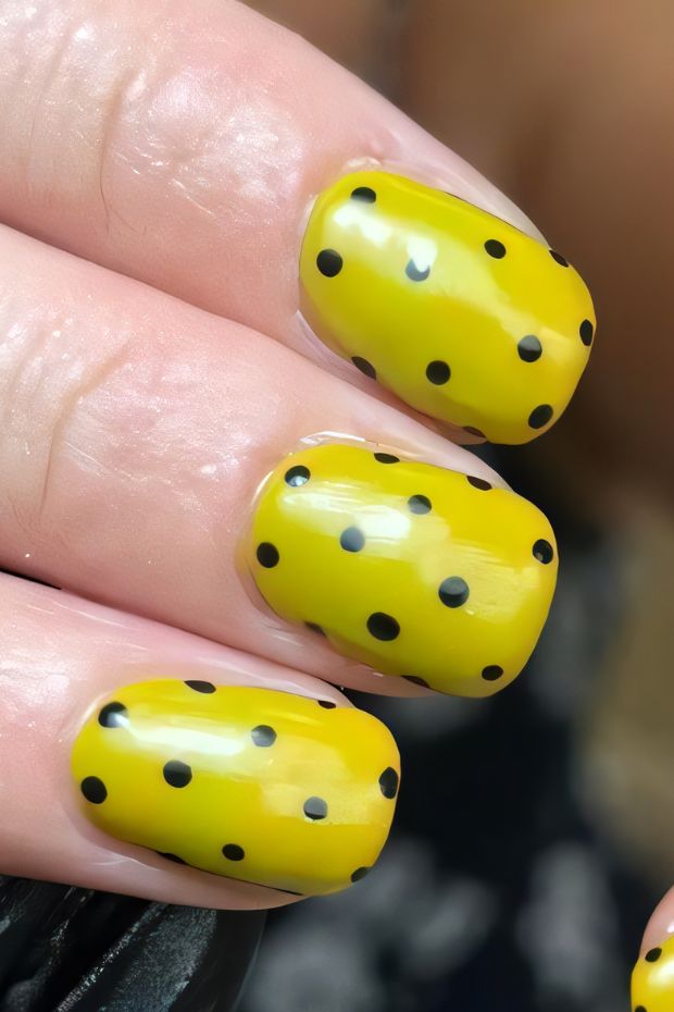 Yellow nails with black polka dots, vibrant nail art design perfect for summer and casual fashion.