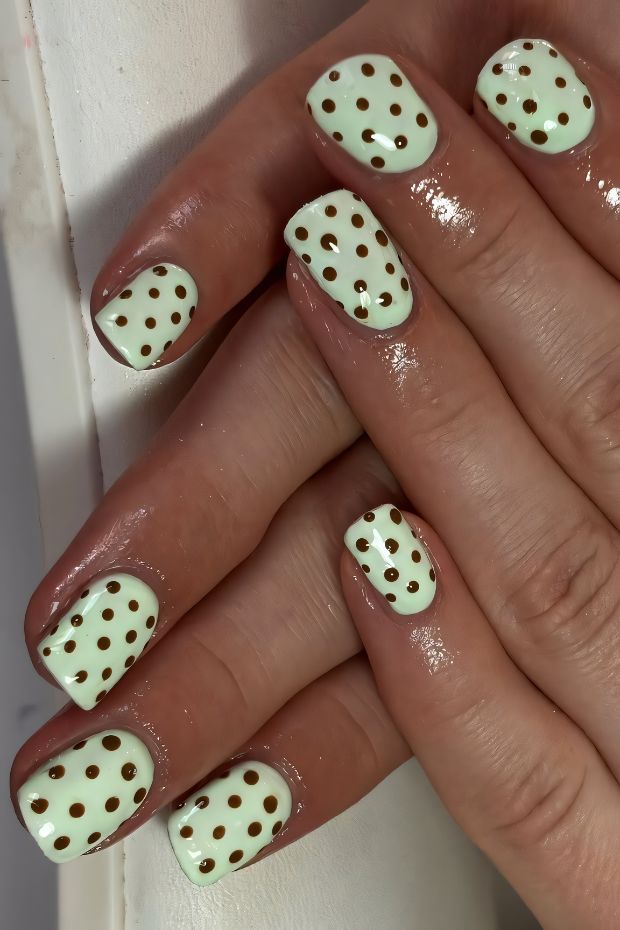 Mint green nails with bronze polka dot design showcasing a playful and chic nail art style.