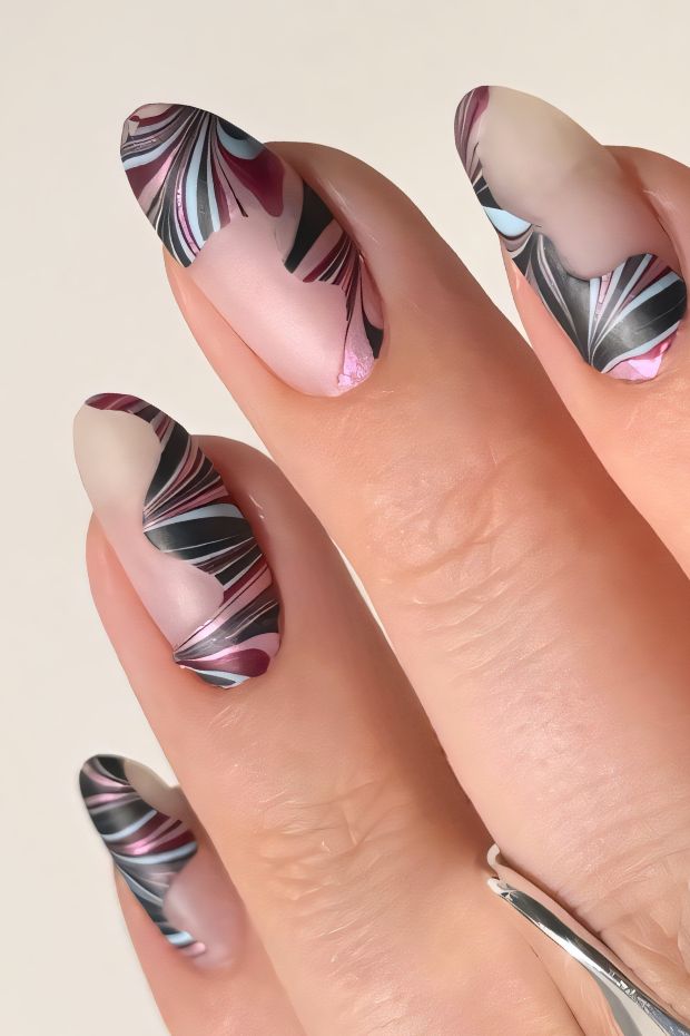 Chic winter nails featuring intricate swirls in burgundy, pink, and black, ideal for the winter season.