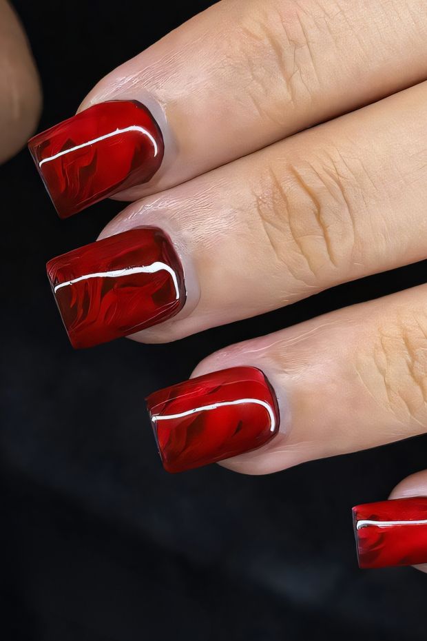 Marble red nails design featuring glossy finish and unique patterns for a bold nail art look.