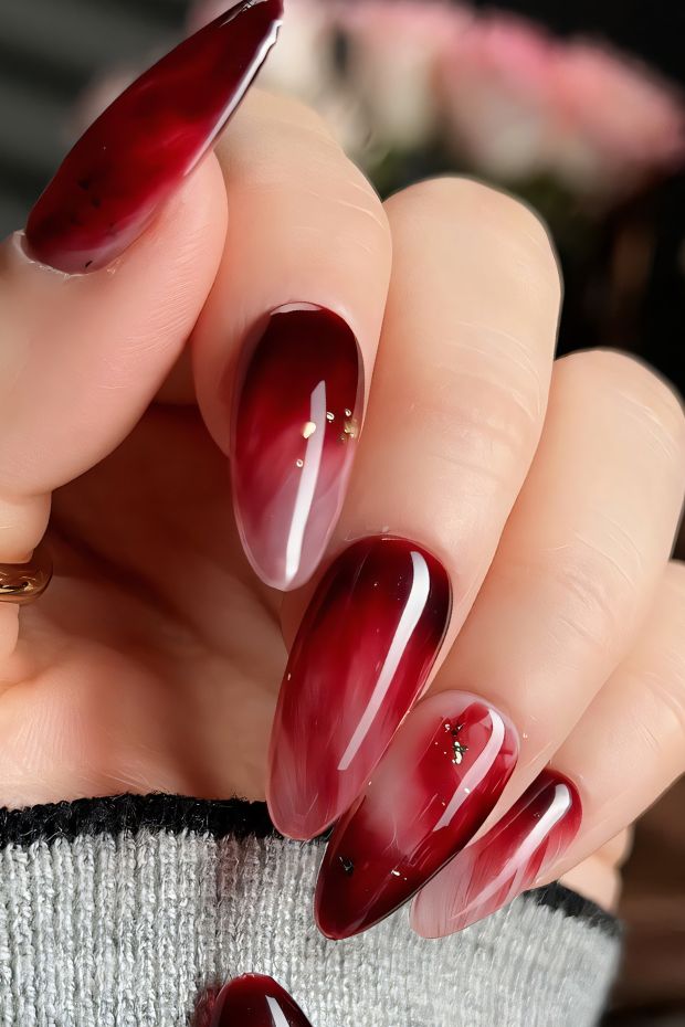 Elegant red ombre nails with gold accents, featuring a glossy finish and eye-catching design for stylish nail art.