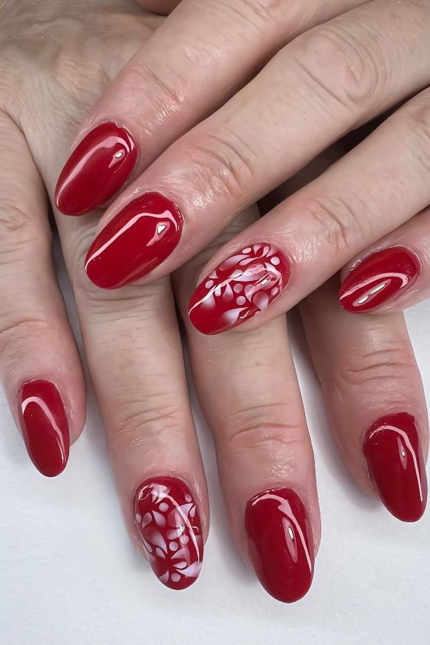 Elegant red nails with artistic white designs for a chic nail art look.
