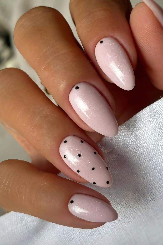 Elegant pink nails featuring a glossy finish with minimalist black dots for a chic nail design.