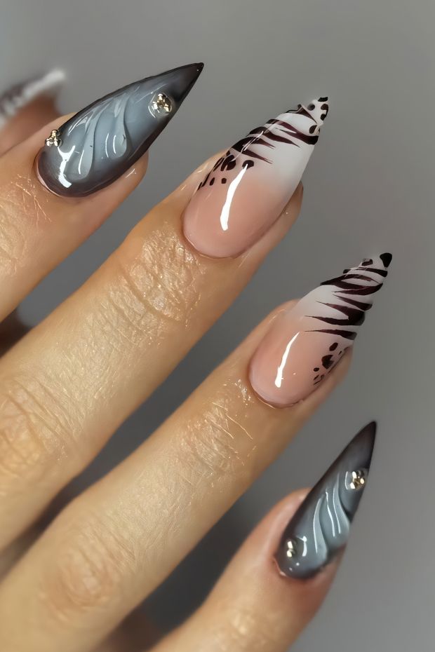 Stiletto nails featuring floral patterns in gray and nude with embellishments, showcasing modern nail art design.