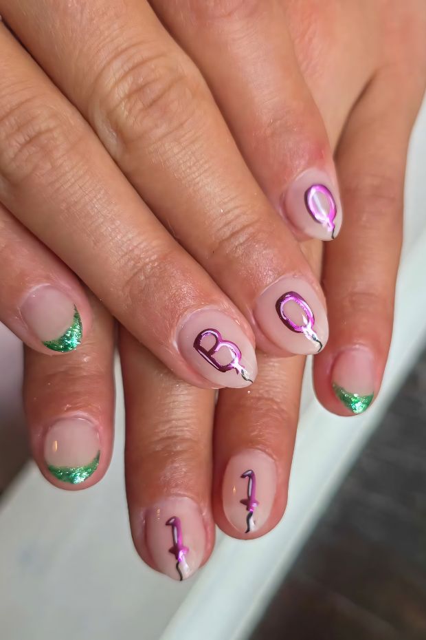 Colorful birthday nail design with vibrant letters and sparkling green tips, perfect for festive celebrations.