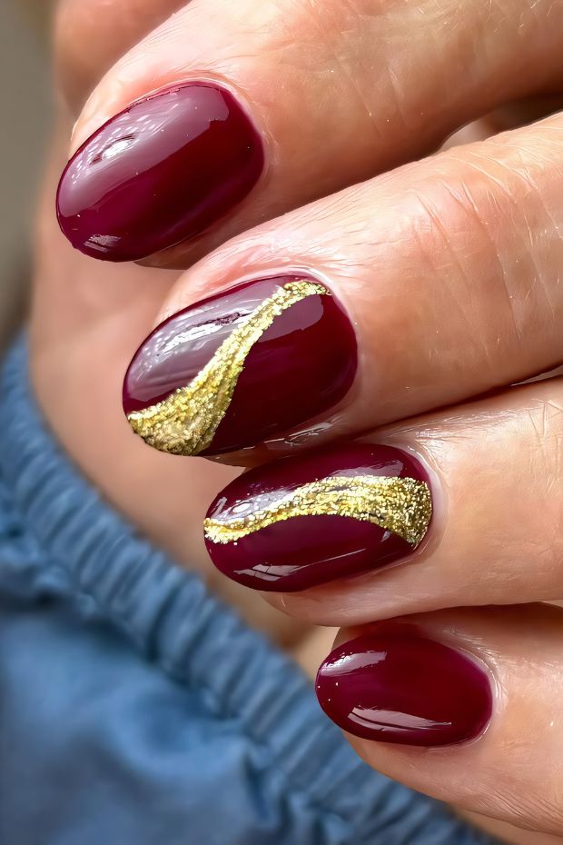 Rich red nails with elegant gold accents creating a sophisticated nail design for a chic look.